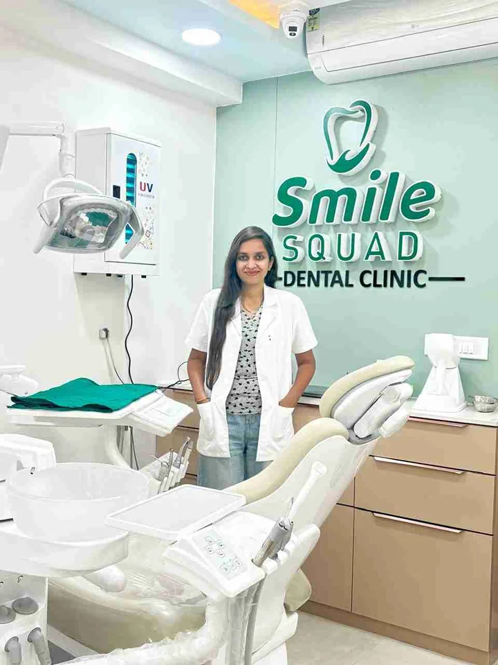 Treatment room at Smile Squad Dental Clinic with a dental chair, a dentist standing in front of the clinic sign